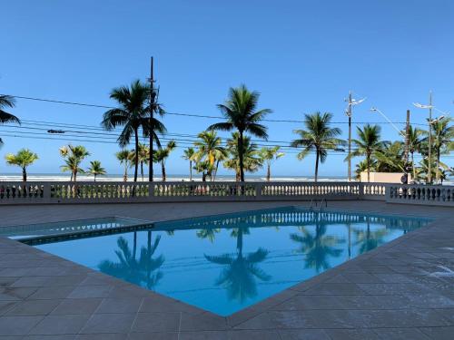 a swimming pool with palm trees in the background at Apartamento frente ao mar com varanda e piscina in Praia Grande