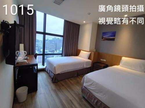a hotel room with two beds and a window at Honest & Warm Hotel in Taoyuan