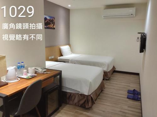a hotel room with two beds and a desk at Honest & Warm Hotel in Taoyuan