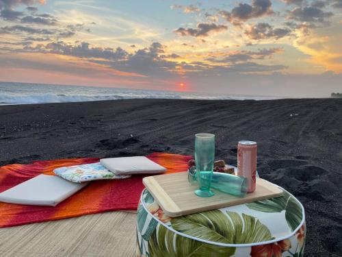 a blanket on the beach with a tray and a bottle at Wave nSea Monterrico in Monterrico