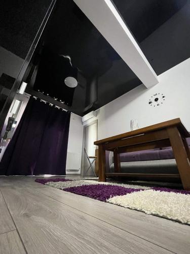 ein Wohnzimmer mit einem Bett und einem lila Teppich in der Unterkunft Roxy apartament in Constanţa