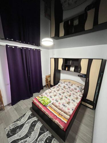 Bett in einem Zimmer mit lila Vorhängen in der Unterkunft Roxy apartament in Constanţa