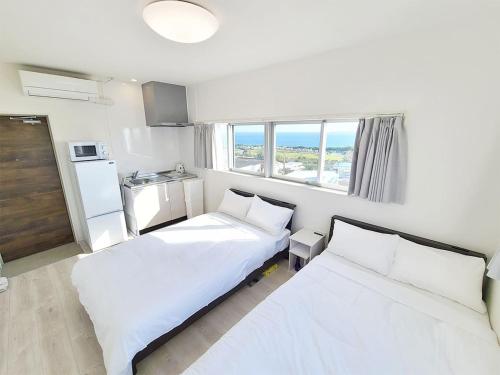 宮古島的住宿－HOTEL Kuu，酒店客房设有两张床和窗户。