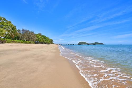 a sandy beach with a pier in the ocean at Alassio Absolute Beachfront Suite 201 Palm Cove in Palm Cove