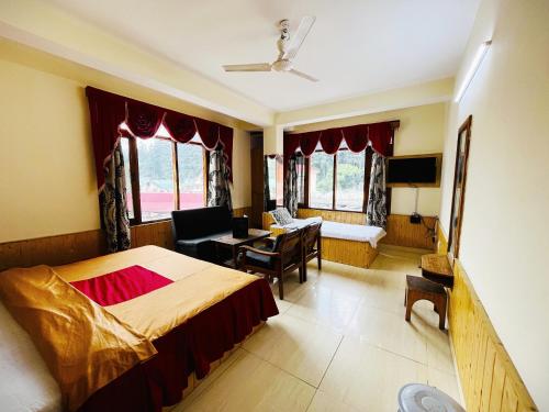 a bedroom with a bed and a desk and a couch at Hotel Snow Mountain Mall Road in Manāli