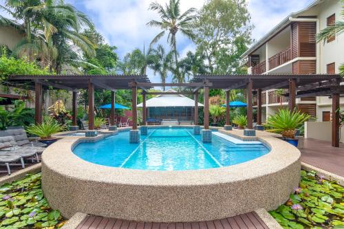 a swimming pool with a pergola next to a building at Seascape Holidays at 30 Tropic Style in Port Douglas