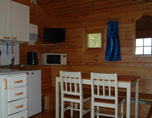 a kitchen with a table and chairs in a cabin at Emolahti Camping in Pyhäjärvi