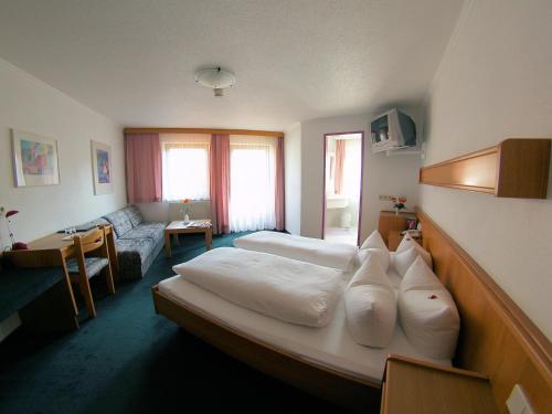 ein Hotelzimmer mit einem Bett und einem Sofa in der Unterkunft Hotel Montana in Arzl im Pitztal