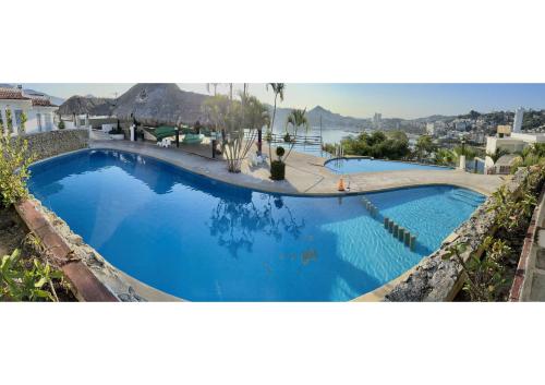 a large blue swimming pool with a view of the ocean at Suite CasaBlanca Grand, la mejor vista de Acapulco in Acapulco