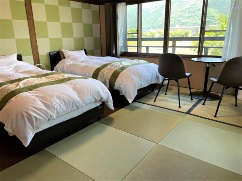 una camera da letto con due letti, un tavolo e delle sedie di Sanso Tanaka a Yufu