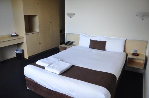 a hotel room with a large bed with towels on it at City Park Hotel in Melbourne