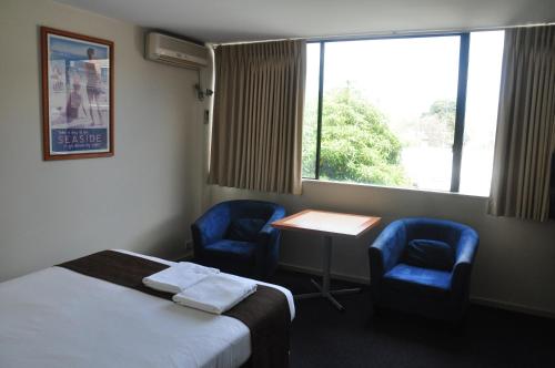 a room with a bed and two chairs and a table and a window at City Park Hotel in Melbourne