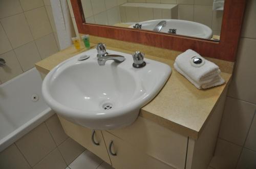 a white sink in a bathroom with a mirror at City Park Hotel in Melbourne