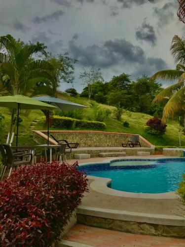 a swimming pool with a table and an umbrella at Finca Mirador la Giralda in Roldanillo