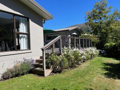 a house with a wooden staircase next to a yard with flowers at Family Home on Inverness in Arrowtown