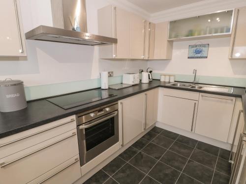 a kitchen with white cabinets and black counter tops at Apartment 6 in Morfa Nefyn