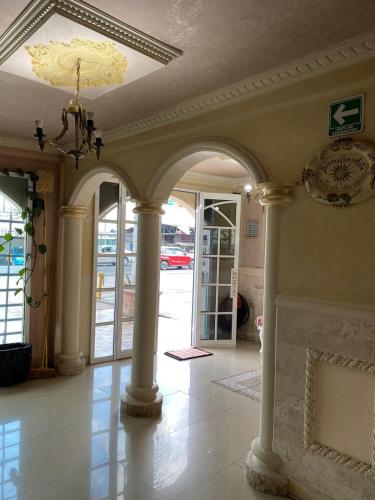 a hallway with columns and a chandelier in a building at Hotel Plaza in San Martín Texmelucan de Labastida
