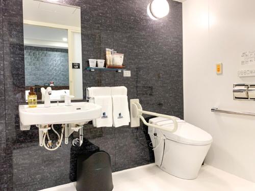 a bathroom with a sink and a toilet and a mirror at HOTEL LiVEMAX Nishinomiya in Nishinomiya