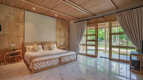 a bedroom with a bed in a room with windows at Pravasa Gili Resort by KajaNe in Gili Meno