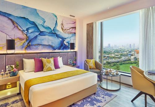 a bedroom with a large bed and a large window at Vivanta Navi Mumbai Turbhe in Navi Mumbai