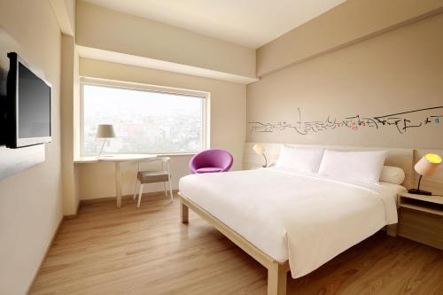1 dormitorio con cama, escritorio y ventana en ibis Styles Jakarta Gajah Mada, en Yakarta