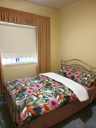 a bedroom with a bed with a floral bedspread and a window at Vacation Getaway in Rowville
