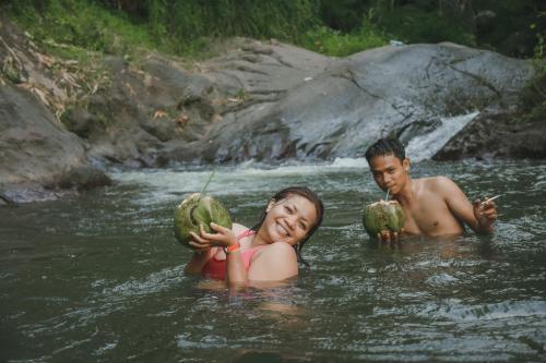 a man and a woman in the water holding coconuts at Lesong Hotel and Restaurant in Munduk