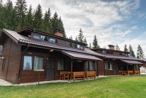 a large wooden house with a lot of windows at Почивна станция Сомат in Dospat