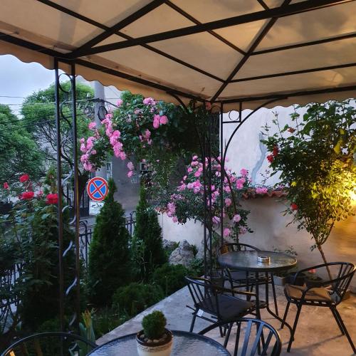 an outdoor patio with tables and chairs and flowers at Guest House Gurkov in Veliko Tŭrnovo