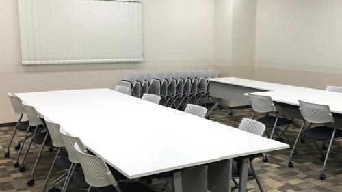 an empty classroom with white tables and chairs at Toyoko Inn Tsushima Hitakatsu in Tsushima