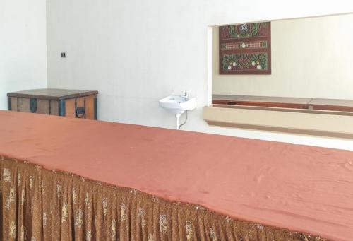 a room with a bed and a sink and a window at Hotel Mataram Cipanas Syariah Mitra RedDoorz in Pasakon 1