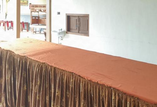 a bed with a brown blanket on top of it at Hotel Mataram Cipanas Syariah Mitra RedDoorz in Pasakon 1