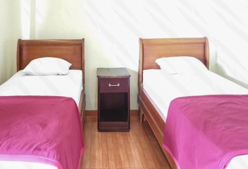 two beds in a room with pink sheets at Hotel Mataram Cipanas Syariah Mitra RedDoorz in Pasakon 1