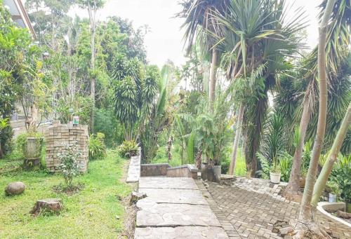 a stone path in a garden with palm trees at Hotel Mataram Cipanas Syariah Mitra RedDoorz in Pasakon 1