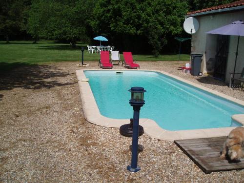a dog is sitting next to a swimming pool at Rowland's French Retreat in La Rochebeaucourt-et-Argentine