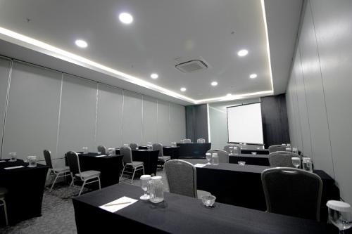 a conference room with tables and chairs and a screen at Laska Hotel Subang in Subang