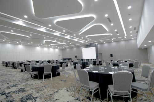 a conference room with tables and chairs and a screen at Laska Hotel Subang in Subang
