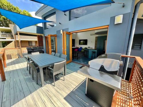 a wooden deck with a table and blue umbrellas at Sails to Sea - 4 Bedroom Pet Friendly in Pambula Beach