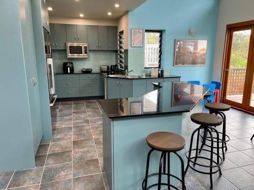 a kitchen with two bar stools and a counter at Sails to Sea - 4 Bedroom Pet Friendly in Pambula Beach