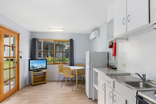 a kitchen with a table and a refrigerator at Wairo Beach Holiday Park in Lake Tabourie