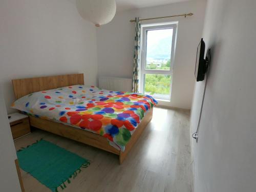 una camera da letto con un letto con un piumone colorato e una finestra di Panoramic Residence a Zărneşti