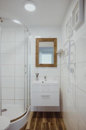 a white bathroom with a sink and a shower at 8 Sosen Pobierowo in Pobierowo