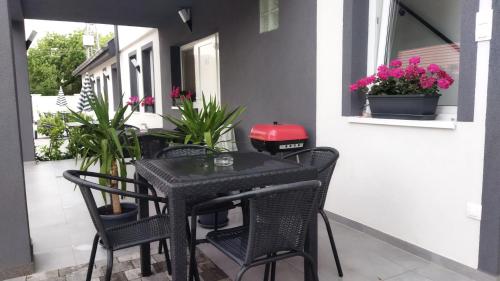 a black table and chairs on a porch with flowers at Holdudvar Apartman in Gyula