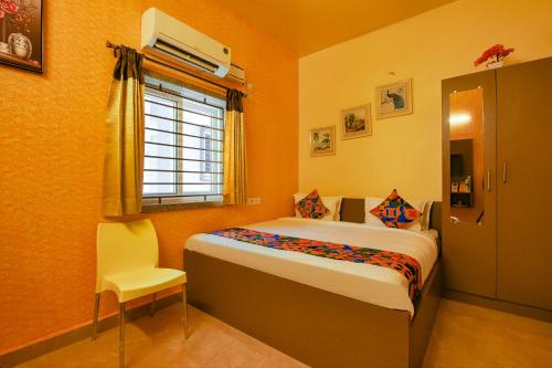 a bedroom with a bed and a window and a chair at FabHotel Vijaylakshmi Stay Inn in Chennai