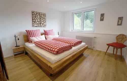 Schlafzimmer mit einem Bett mit roten und weißen Kissen in der Unterkunft Gummeneck - Stubenhof, Black Forest in Simonswald