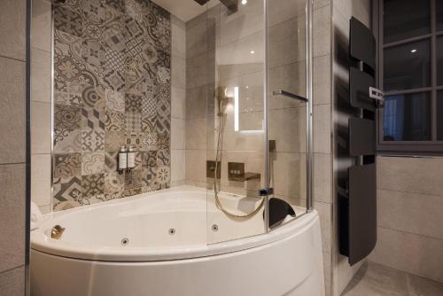 a bathroom with a tub and a glass shower at LE PETIT MANOIR in Sarlat-la-Canéda