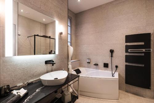 a bathroom with a white tub and a sink at LE PETIT MANOIR in Sarlat-la-Canéda