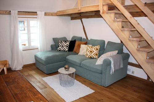 a living room with a blue couch and stairs at Wohnung Alter Heuboden im Fachwerk bei Bonn Alfter in Heidgen