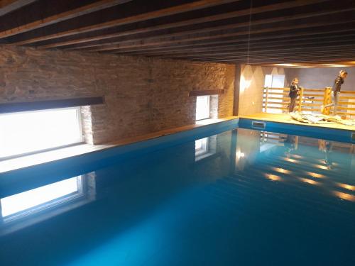 une piscine avec des personnes debout en arrière-plan dans l'établissement le king conde, à Condé-sur-Noireau