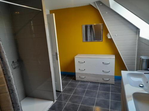 a bathroom with a sink and a shower and yellow wall at le king conde in Condé-sur-Noireau